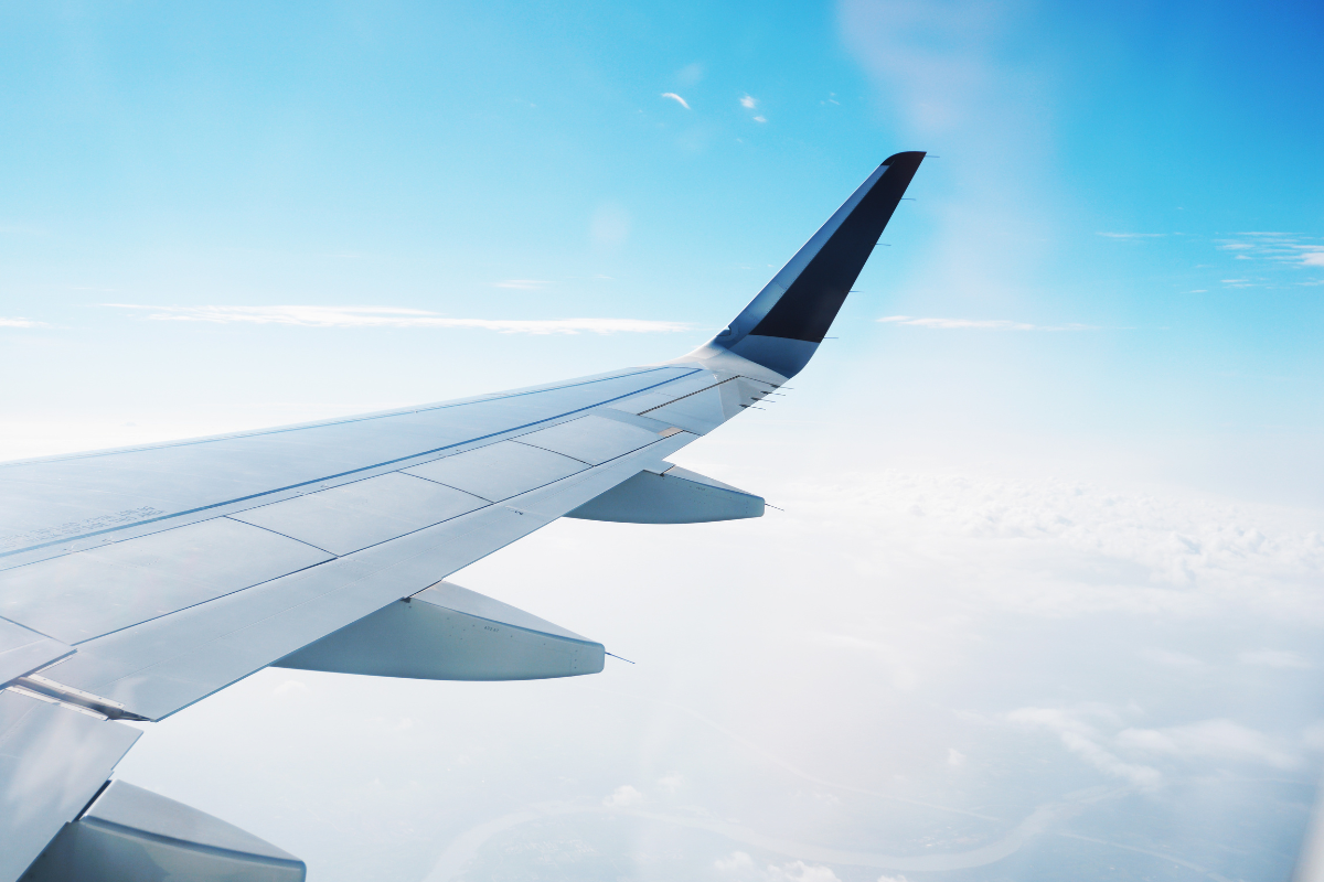 The wing of a large airplane, flying in the blue sky.