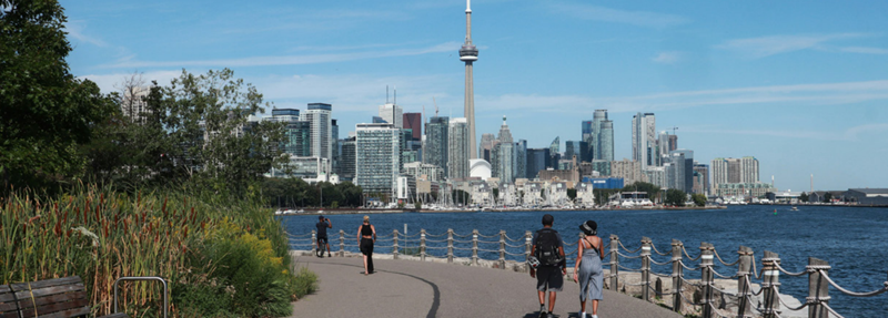 People walking along the shoreline of Toronto.