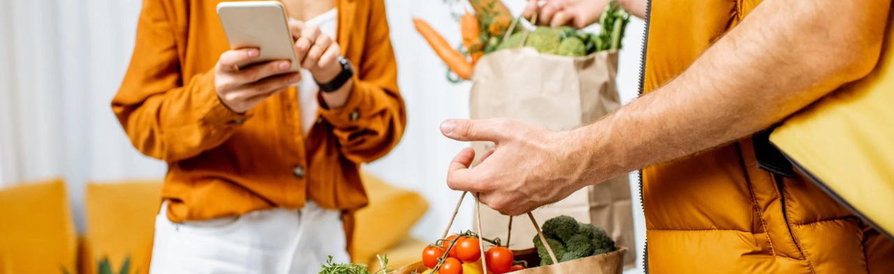 Man delivering groceries to woman on smartphone app