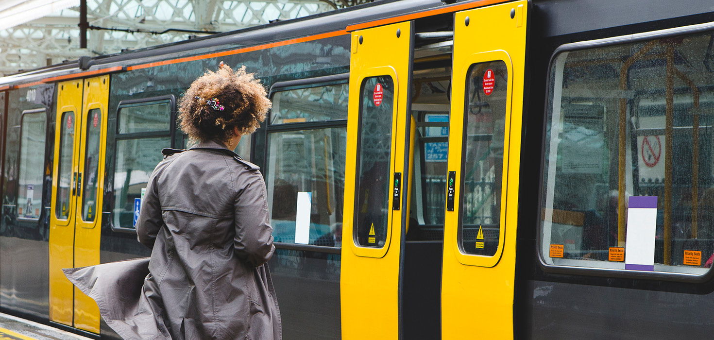 With the doors slightly ajar, a woman approaches an approaching train.