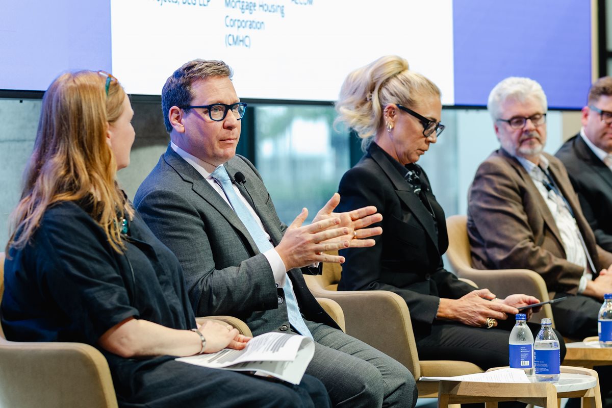 A panel of people sit on stage while one person is speaking