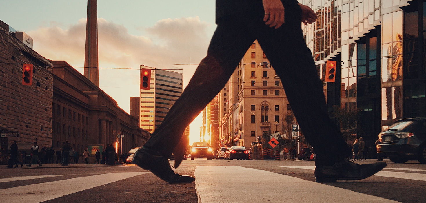 Man crossing downtown street at dusk