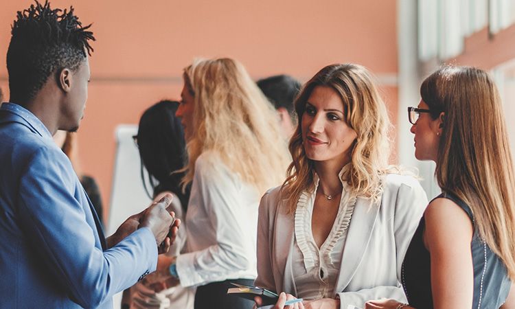 Man engaging in conversation with two women at a networking event.