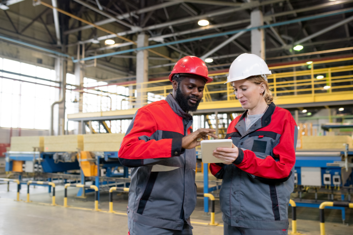 Two colleagues look at a plan together in a factory.