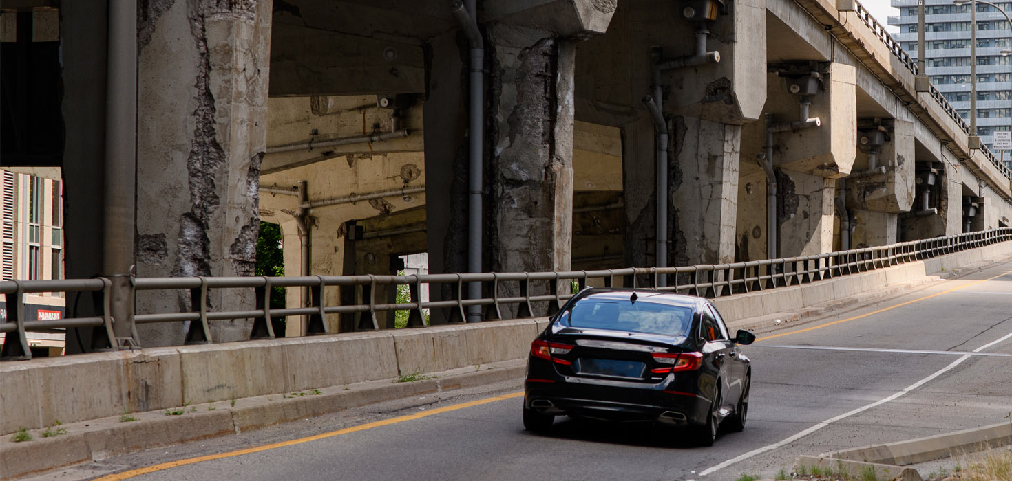 Image of a lone car entering the Gardiner on-ramp.