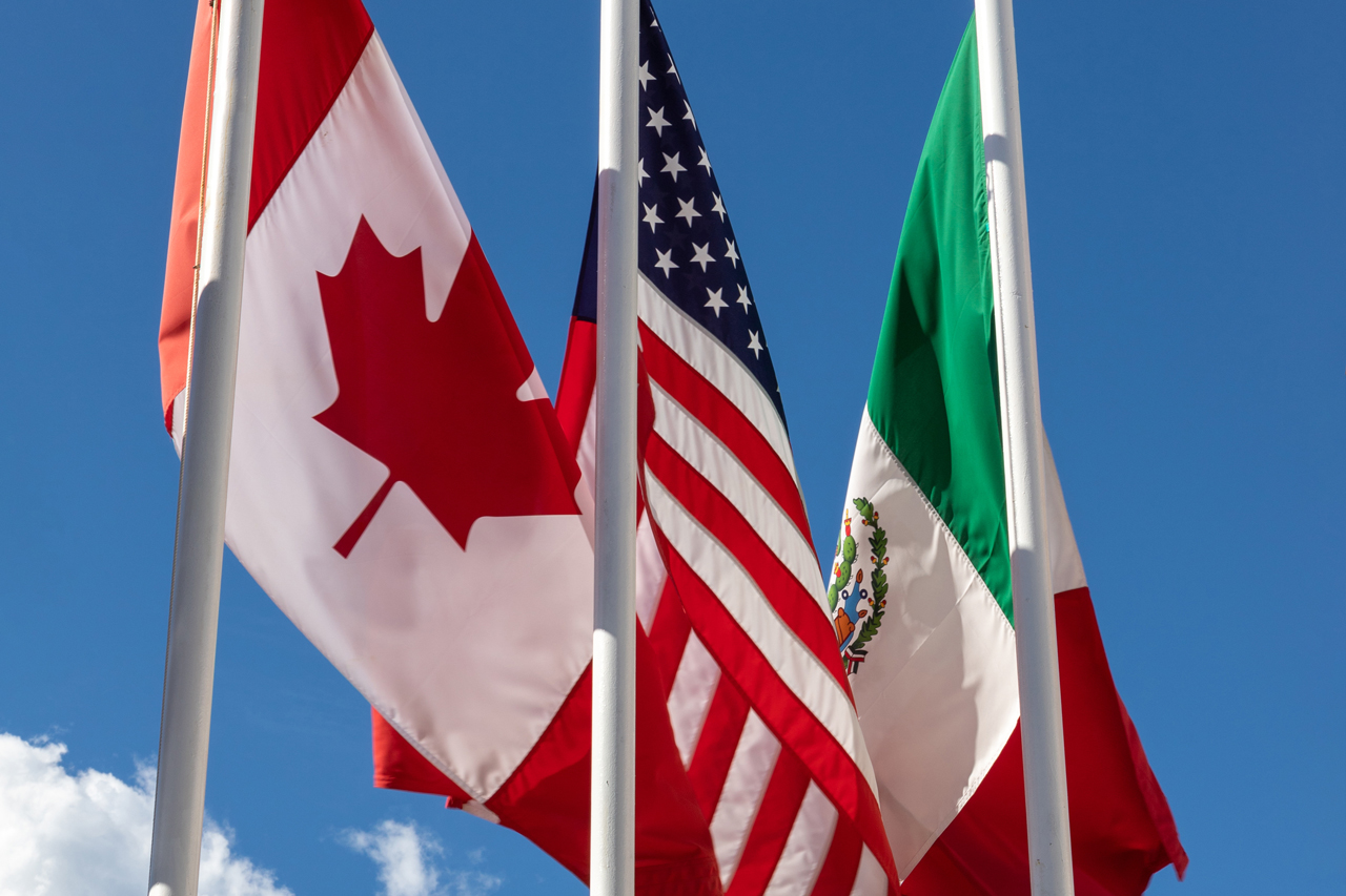 Flags of Canada, USA and Mexico against a blue sky